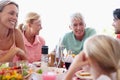 Grandpa is telling them some stories. a multi-generational family having lunch together at an outdoor table.