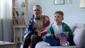 Grandpa wrapped in American flag watching sport with boy, worrying about game Royalty Free Stock Photo