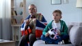 Grandpa wrapped in British flag watching soccer with boy, worrying about game Royalty Free Stock Photo