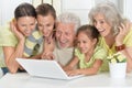 Grandparents with adult daughter and grandchildren using laptop