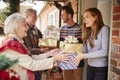 Grandparents Being Greeted By Family As They Arrive For Visit On Christmas Day With Gifts Royalty Free Stock Photo