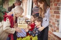 Grandparents Being Greeted By Family As They Arrive For Visit On Christmas Day With Gifts Royalty Free Stock Photo