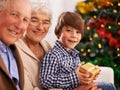 Grandparents, child and Christmas gift as portrait for festive season celebration for tradition, presents or bonding Royalty Free Stock Photo