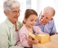 Grandparents, child and opening gift box for birthday or special event, old people and young girl for celebration Royalty Free Stock Photo