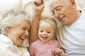 Grandparents Cuddling Granddaughter In Bed