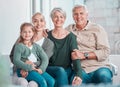 Grandparents, girl and mother in portrait on couch with hug, care or bonding with love in family home lounge. Elderly