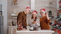 Grandparents with grandchild wearing santa hat greeting remote friends during online videocall