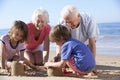 Grandparents And Grandchildren Building Sandcastle On Beach