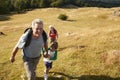 Grandparents With Grandchildren Climbing Hill On Hike Through Countryside In Lake District UK Together