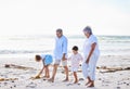 Grandparents and grandchildren holding hands while walking along the beach. Senior couple enjoying summer vacation with Royalty Free Stock Photo