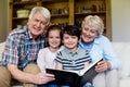 Grandparents and grandchildren holding photo album in living room Royalty Free Stock Photo