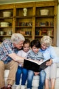 Grandparents and grandchildren looking at photo album in living room Royalty Free Stock Photo