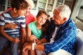 Grandparents and grandchildren looking at smartwatch in living room Royalty Free Stock Photo