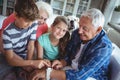 Grandparents and grandchildren looking at smartwatch in living room Royalty Free Stock Photo