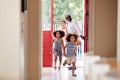 Grandparents With Grandchildren Returning Home From Shopping Trip Carrying Grocery Bags