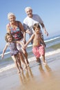 Grandparents And Grandchildren Running Along Beach Royalty Free Stock Photo