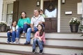 Grandparents With Grandchildren Sit On Steps Leading Up To Home Royalty Free Stock Photo