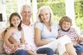 Grandparents And Grandchildren Sitting On Cane Sofa At Home Royalty Free Stock Photo