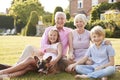 Grandparents and grandchildren sitting in garden with dog