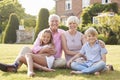 Grandparents and grandchildren sitting on grass in a garden Royalty Free Stock Photo