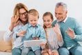 grandparents and grandchildren waving by hands while having video call with digital tablet