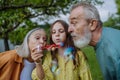 Grandparents and granddaughter are blowing bubbles from a bubble wand. Royalty Free Stock Photo