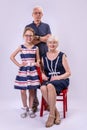 Grandparents and granddaughter on a gray background in full length