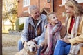 Grandparents With Granddaughter And Pet Dog Outside House Getting Ready To Go For Winter Walk Royalty Free Stock Photo