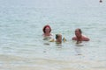 Grandparents And Granddaughter swimming in the sea, they smile and happyness