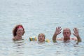 Grandparents And Granddaughter swimming in the sea, they smile and happyness