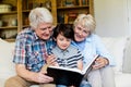 Grandparents and grandson looking at photo album in living room Royalty Free Stock Photo