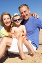 Grandparents And Grandson Sitting On Beach