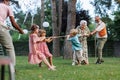 Grandparents have a tug of war with their grandkids. Fun games at family garden party.