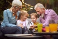 Grandparents laughing, enjoying with their grandchildren, sitting outdoor on sofa in the backyard, having fun Royalty Free Stock Photo