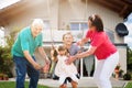 Grandparents Looking At Their Grandchildren Playing On Swing Royalty Free Stock Photo