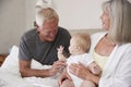 Grandparents Lying In Bed At Home Looking After Baby Grandson Royalty Free Stock Photo