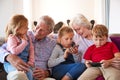 Grandparents Playing Video Games With Grandchildren On Mobile Phones At Home Royalty Free Stock Photo