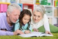 Grandparents reading book with little granddaughter