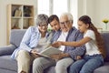 Grandparents reading a book to their grandchildren sitting at sofa at home. Royalty Free Stock Photo