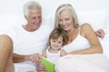 Grandparents reading to granddaughter in bed Royalty Free Stock Photo