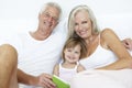 Grandparents Reading To Granddaughter In Bed