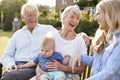 Grandparents Sit Outdoors With Baby Grandson And Adult Daughter