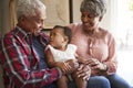 Grandparents Sitting On Sofa With Baby Granddaughter At Home Royalty Free Stock Photo