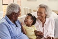 Grandparents Sitting On Sofa At Home Playing With Baby Granddaughter Royalty Free Stock Photo