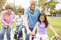 Grandparents Teaching Grandchildren To Ride Bikes In Park Royalty Free Stock Photo