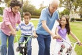 Grandparents Teaching Grandchildren To Ride Bikes In Park Royalty Free Stock Photo