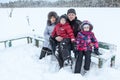 Grandparents walk with their grandchildren on frozen lake, sitting together on wooden bench Royalty Free Stock Photo