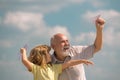 Grandson child and grandfather with paper plane over blue sky and clouds. Men generation granddad and grandchild. Royalty Free Stock Photo