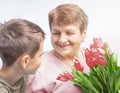 Grandson congratulates grandma (over the age of 50) on holiday. Grandmother has a bunch of flowers. Royalty Free Stock Photo