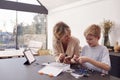 Grandson With Grandmother Assembling Electronic Components To Build Robot Together At Home